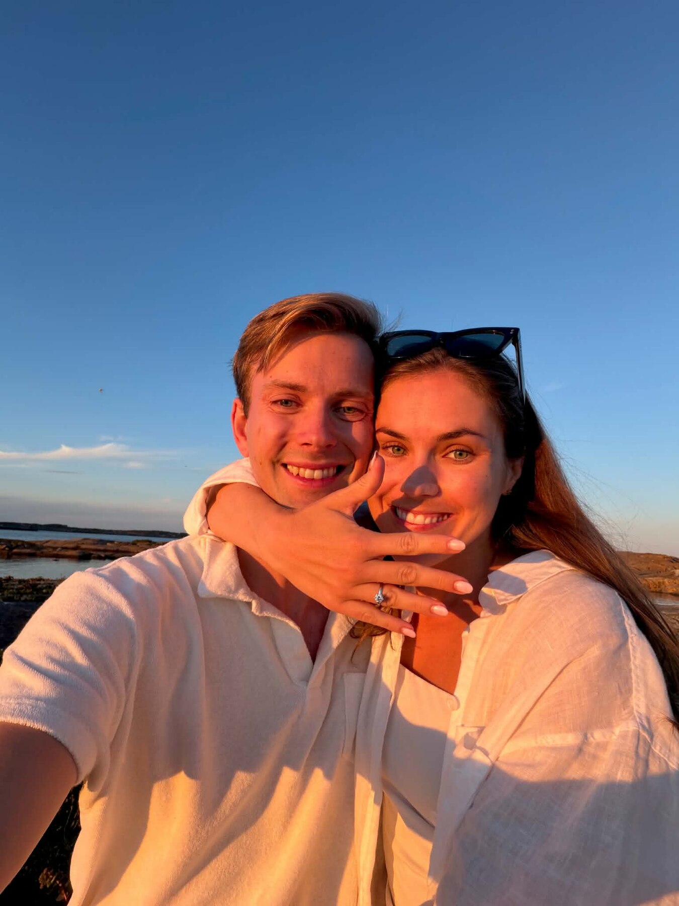 Julie og Sivert ved sjøen i solnedgang, med forlovelsesringen