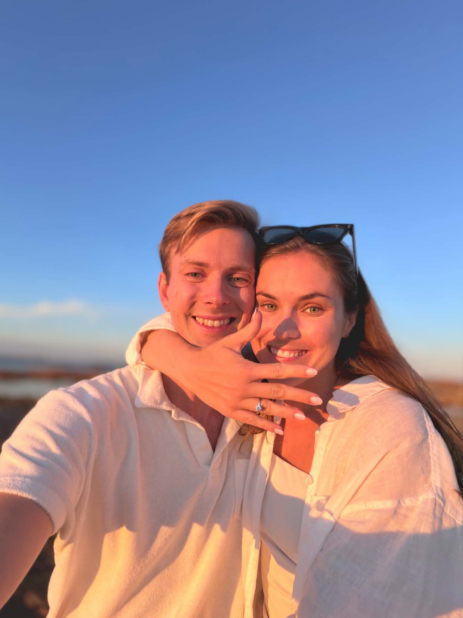 Julie og Sivert ved sjøen i solnedgang, med forlovelsesringen
